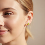white and green 6mm flower earrings in an ear