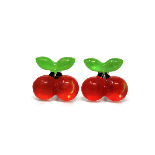 A pair of red cherry-shaped stud earrings with green leaves on top, attached to white posts.