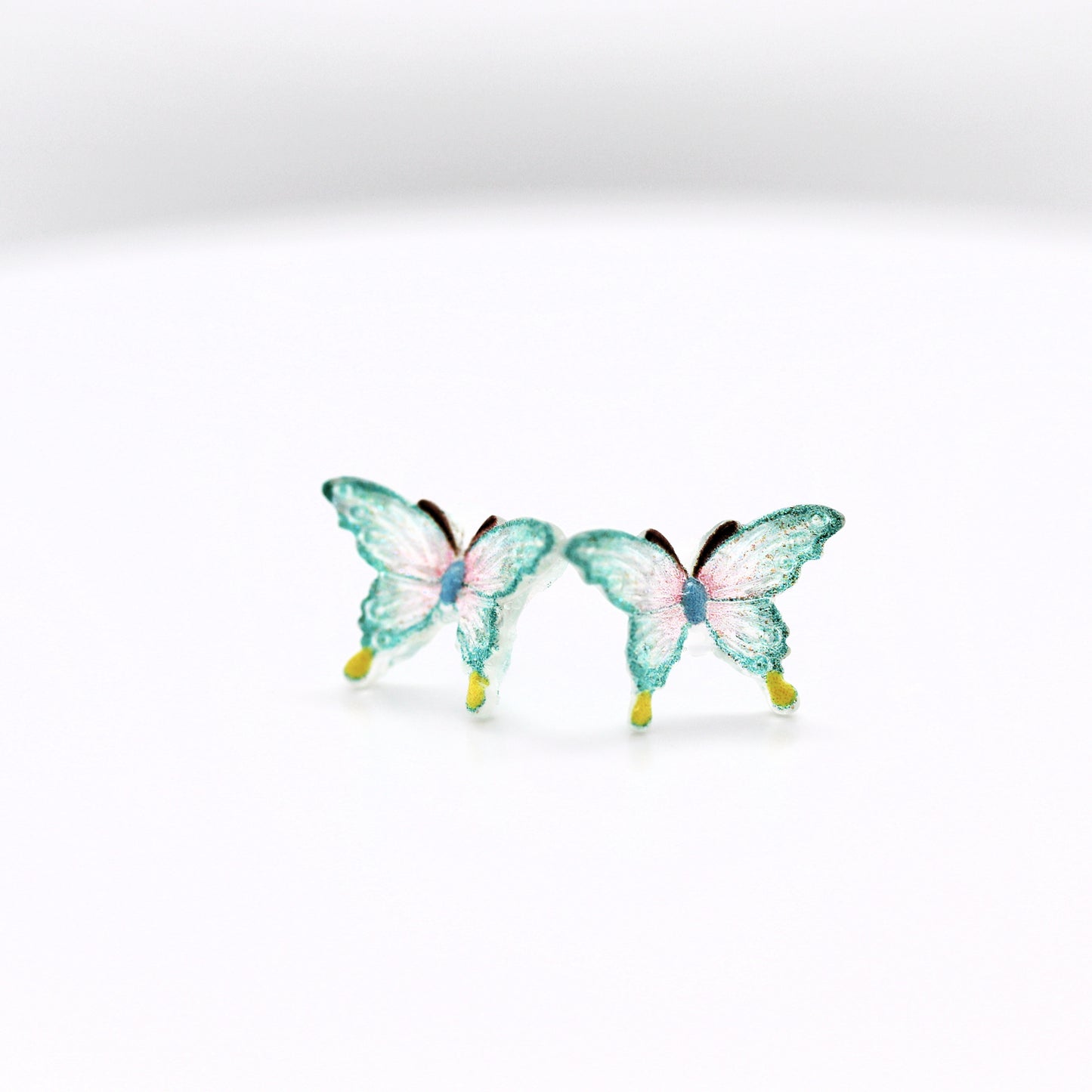 Two aqua butterfly figurines on a white background
