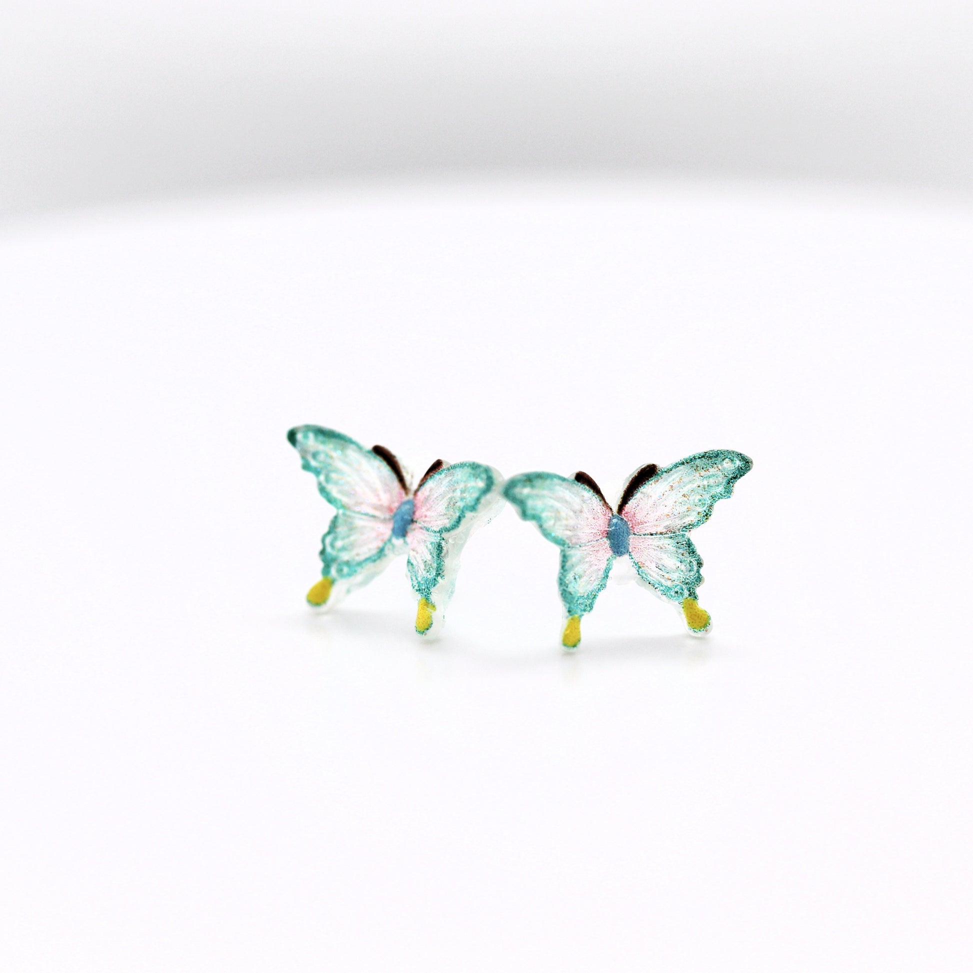 Two aqua butterfly figurines on a white background