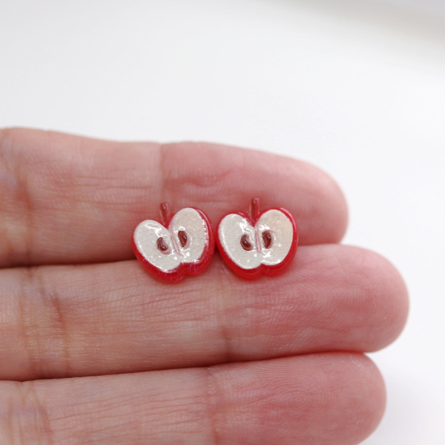 apple stud earrings in a hand