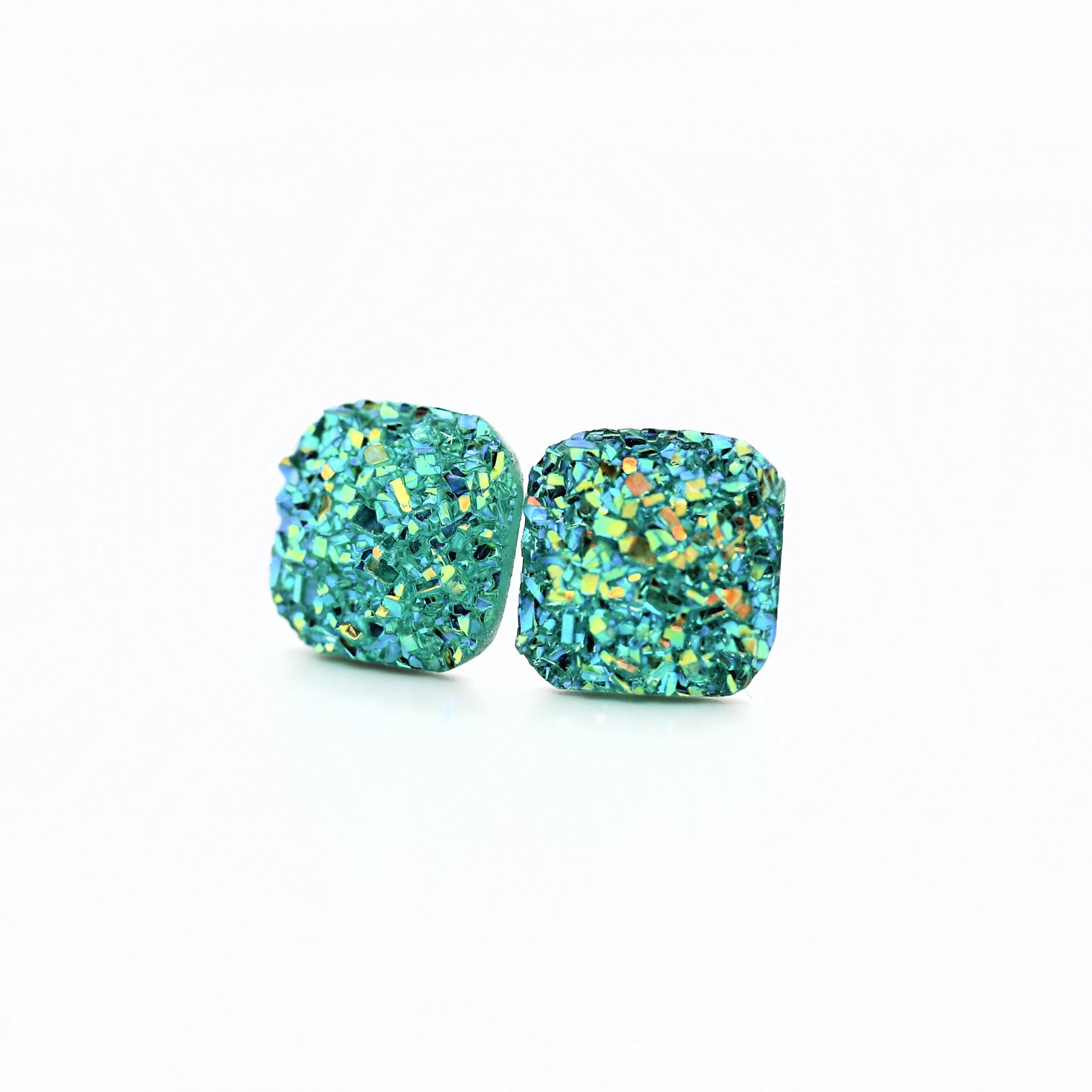 A pair of aqua blue square druzy stud earrings with rounded corners on a white background, with a text overlay saying 'More Colors'.
