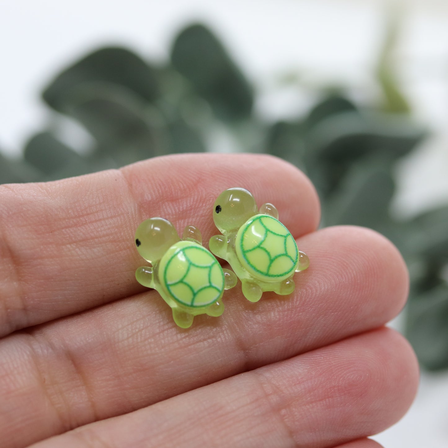 green turtle earrings in a hand