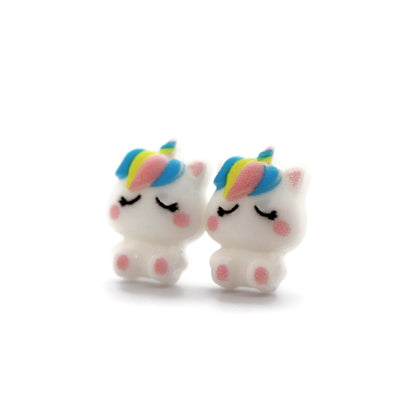A pair of white unicorn stud earrings with rainbow-colored manes, crafted from resin, displayed against a white background.