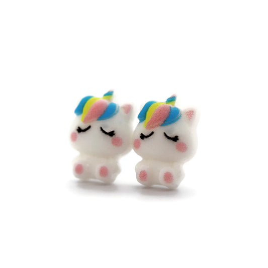 A pair of white unicorn stud earrings with rainbow-colored manes, crafted from resin, displayed against a white background.