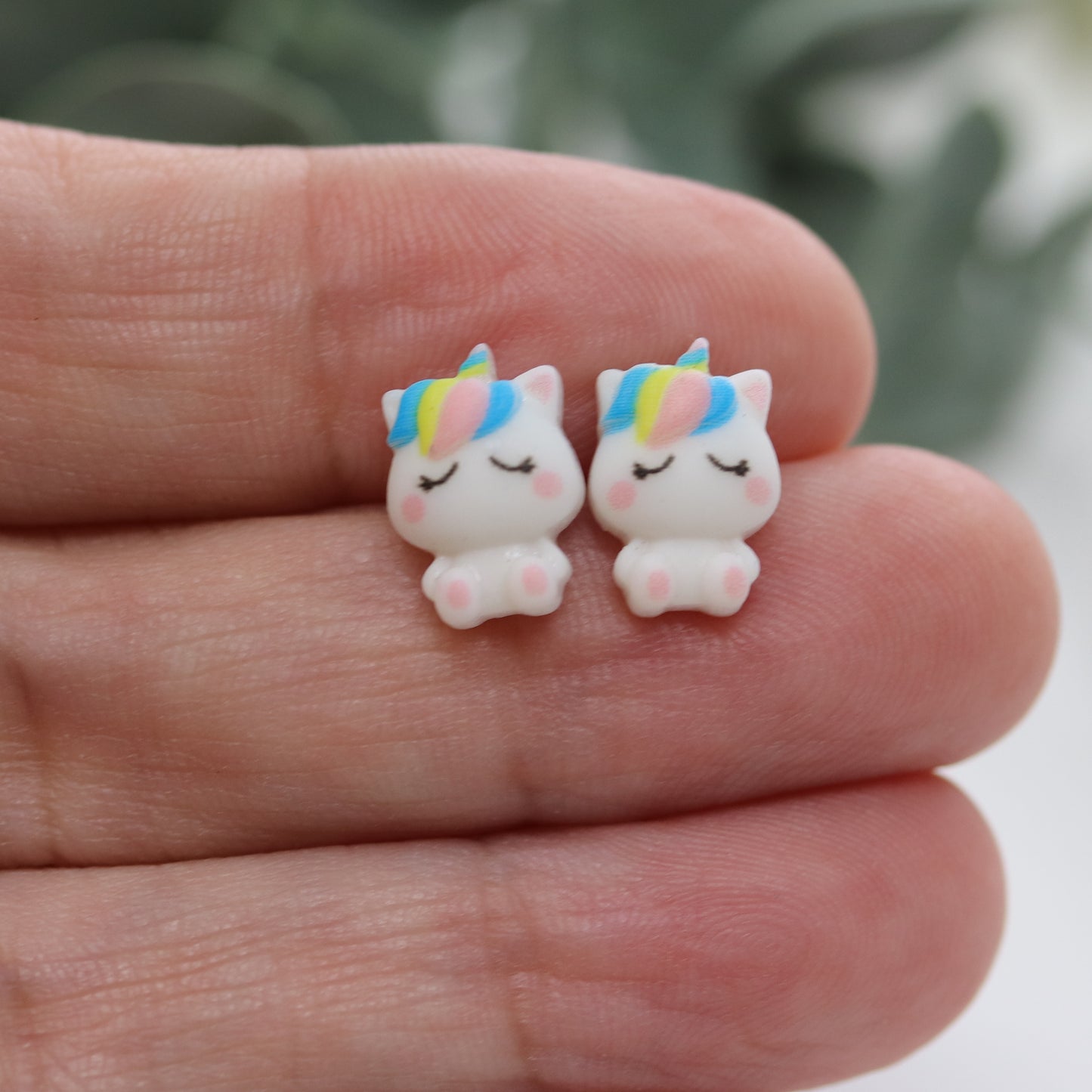 white unicorn earrings in a hand