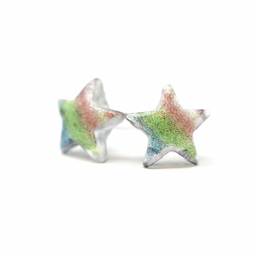 A pair of multicolor glitter star-shaped stud earrings on a white background.
