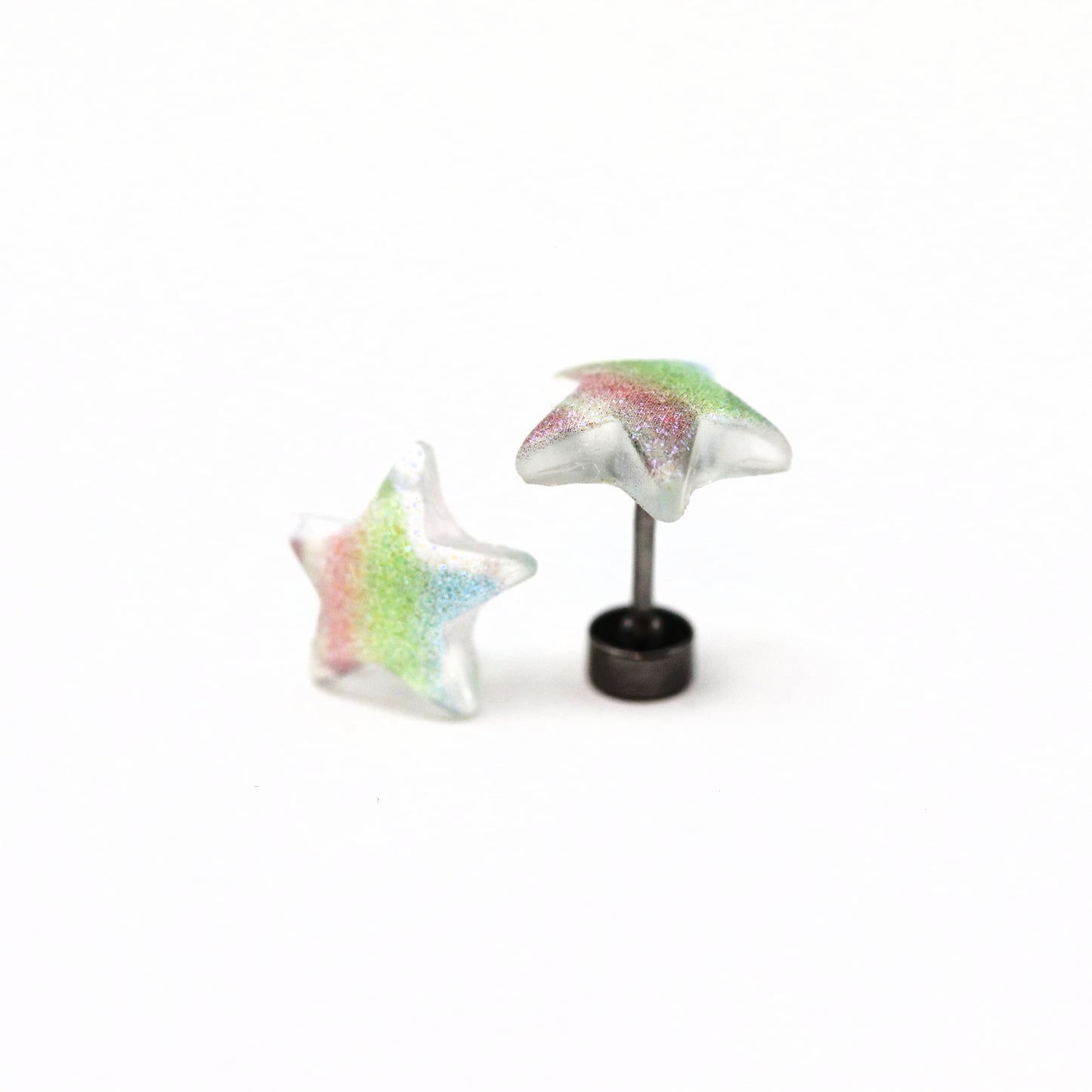 A pair of multicolor glitter star-shaped stud earrings on a white background.