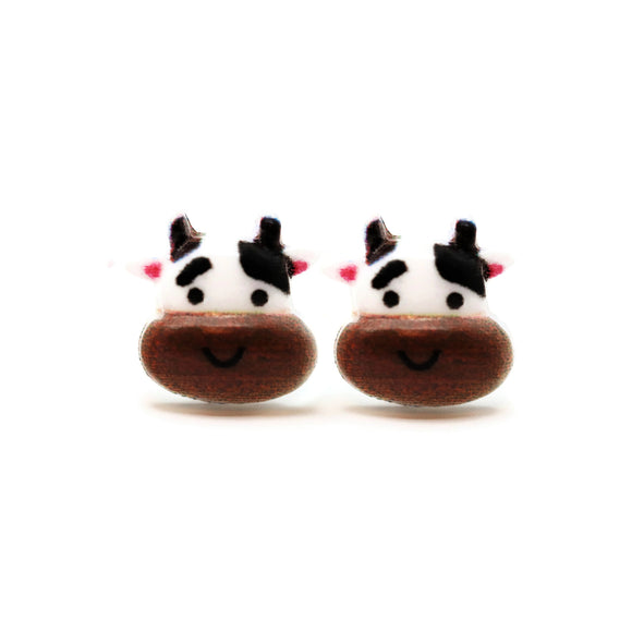 Pair of cow-shaped earrings with cartoon faces on a white background