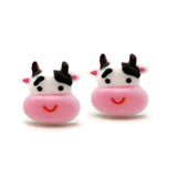 Two pink cow-shaped earrings with black, pink and white faces on a white background