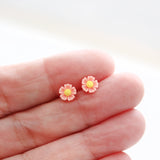 coral flower earring between fingers