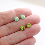 aqua and green flower earrings in a hand