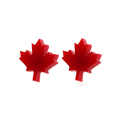 A pair of red maple leaf-shaped stud earrings against a white background.