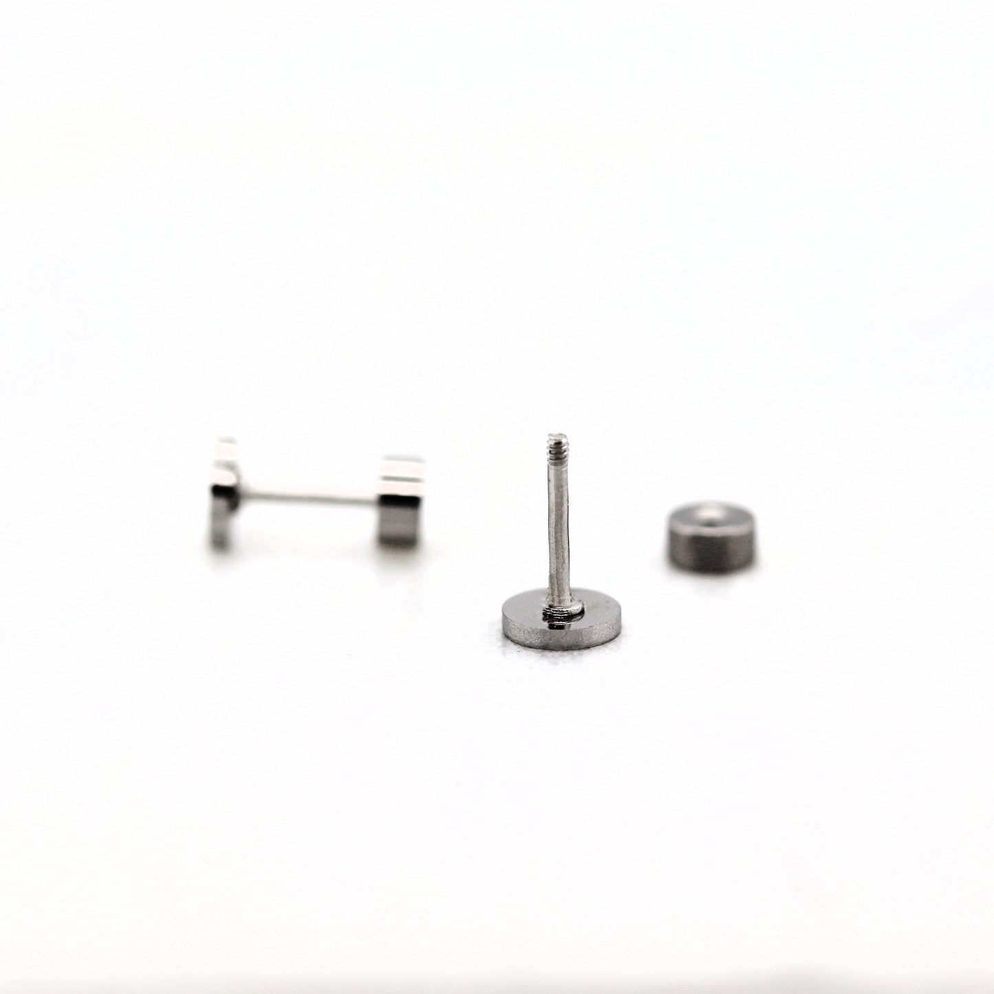 A stainless steel flat screw back earring post with a threaded post, accompanied by two small flat pads for attachment.