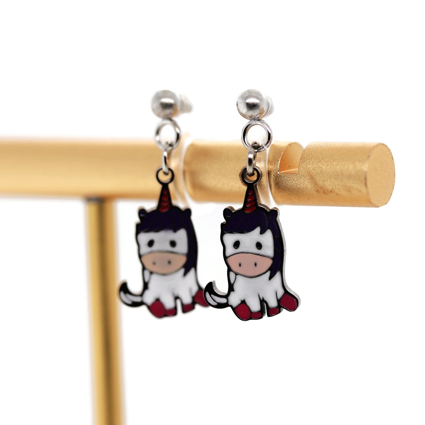 Unicorn-shaped earrings on a gold stand against a white background