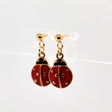 Red ladybug earrings with gold accents on a white background