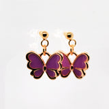 Butterfly-shaped earrings with purple wings and gold accents on a white background