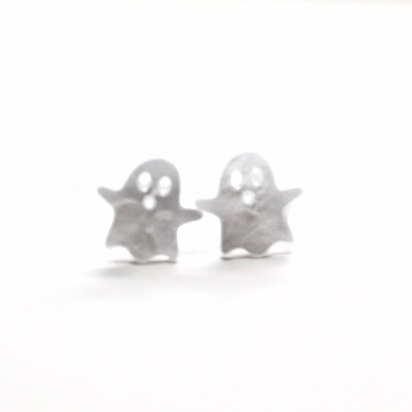 Silver ghost-shaped earrings on a white background