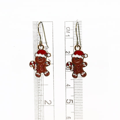 Gingerbread man earrings with a ruler for scale on a white background
