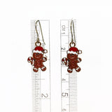 Gingerbread man earrings with a ruler for scale on a white background