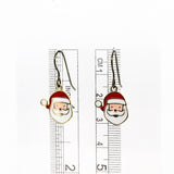 Santa Claus-themed earrings with a ruler for scale on a white background