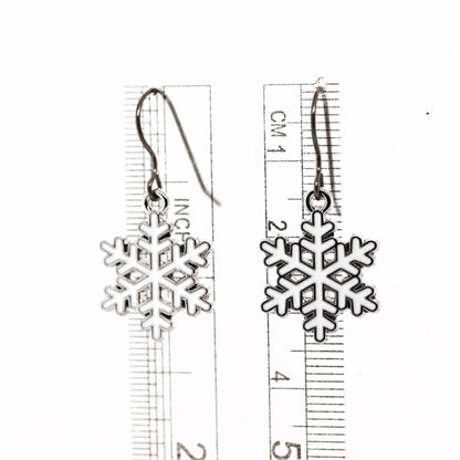 Snowflake earrings with a ruler for scale on a white background