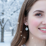 Close-up of a person wearing snowflake earrings with a blurred background