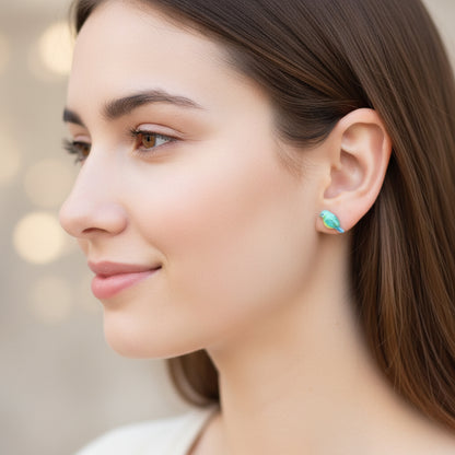 Close-up of an ear with two earrings: a colorful bluebird one and a rhinestone one.