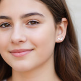 Close-up of an ear wearing small earrings one paw print two rhinestones