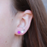 Close-up of an ear wearing a purple earring and a silver earring.