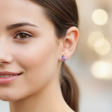 Close-up of an ear wearing two earrings: a pink ladybug earring and a silver earring.