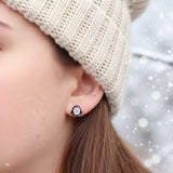 Close-up of an ear wearing small earrings, shaped like a penguin 