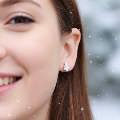 Close-up of an ear wearing  small tree earrings with a snowy background