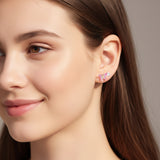Close-up of an ear wearing pink clip-on earrings with a butterfly design.