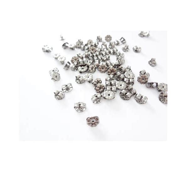 A collection of silver-colored titanium petal style earring backs scattered on a white surface.