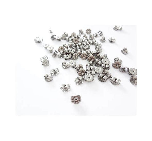 A collection of silver-colored titanium petal style earring backs scattered on a white surface.