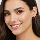 Purple flower-shaped earring on a model against a light gray background