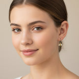 Close-up of an ear with a gold bee-shaped earring and two small stud earrings.