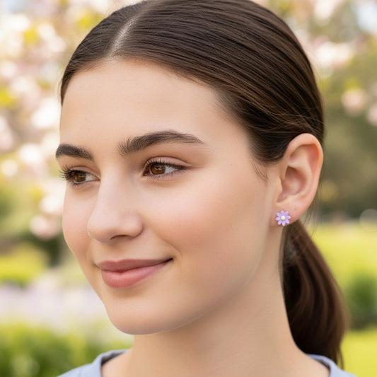 Close-up of an ear with two earrings: a small round earring and a purple flower-shaped earring.
