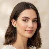 Close-up of an ear wearing a green turtle earring with a blurred background