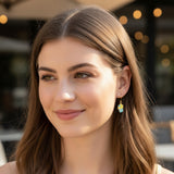 Close-up of an ear with a colorful earring, surrounded by blurred natural background