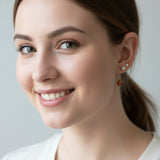 Model wearing a red and gold ladybug earring with a plain background