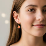 Close-up of an ear wearing a watermelon-shaped earring with a pink background