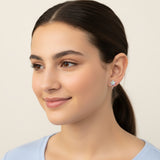 Close-up of an ear with two earrings: a star-shaped earring and a small round earring.