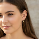 Close-up of an ear with a tiny yellow and blue ice cream earring.