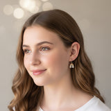 Close-up of an ear wearing a rainbow and flower earring with additional small earrings.