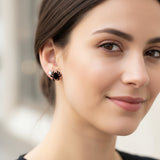 Close-up of an ear with a spider-shaped earring and a clear gemstone earring.