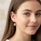Close-up of an ear wearing strawberry-shaped earrings with a neutral background