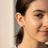 Close-up of an ear wearing a bee-shaped stud earring with a blue garment in the background.