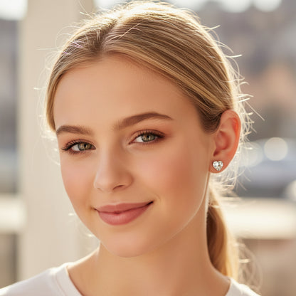Heart-shaped earring worn by a person with blonde hair.